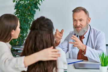 Fototapeta premium beautiful couple talking to grey bearded gynecologist at his office, in vitro fertilization concept