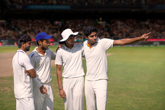 Team mates discussing game plan during a cricket match - Powered by Adobe