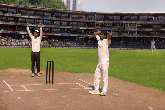 Bowler looking at the boundry as the umpire gives the signal of a sixer, during a cricket match