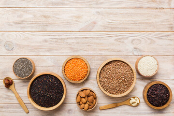 Various superfoods in smal bowl on colored background. Superfood as rice, chia, quinoa, lentils, nuts, sesame seeds, almonds. top view copy space