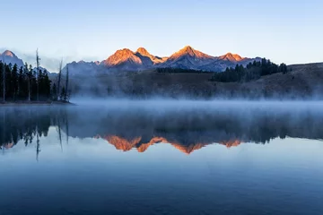 Abwaschbare Fototapete Reflection Redfish lake in Idaho in dawn. Calm water covered by mist. Mountains range is reflecting in lake water