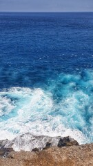 A serene view from a rocky perch overlooking the ocean on Nusa Penida Island, Bali, Indonesia, where nature's beauty meets the endless sea