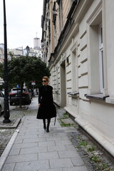 Dojrzała, elegancka kobieta na miejskim spacerze.
Kobieta w czerni.  - obrazy, fototapety, plakaty