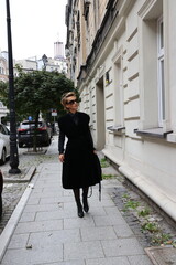 Dojrzała, elegancka kobieta na miejskim spacerze.
Kobieta w czerni.  - obrazy, fototapety, plakaty