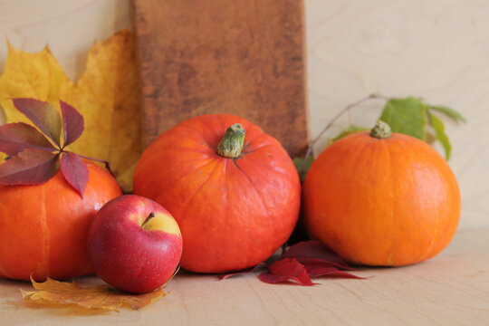 Ripe pumpkins, apples and autumn leaves on a wooden background, side view. Autumn harvest concept. Photos for seasonal banners. Products on the table with selective focus