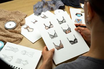 The designer draws sketches of women's underwear. Lingerie panties and bra on paper.