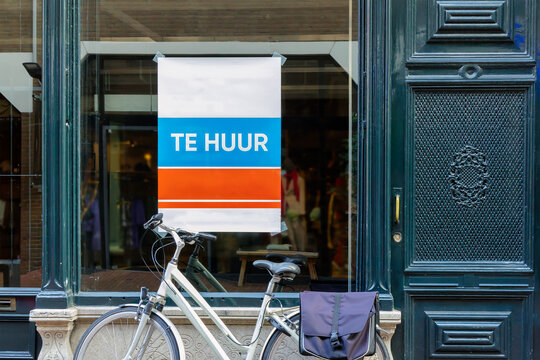 Dutch sign with the text 'for rent' on an empty store window with bicycle in front in Arnhem, The Netherlands