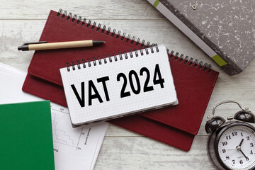 VAT 2024 text on the notebook page. folders and diaries on the table