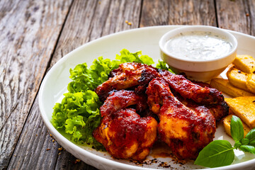 Buffalo wings with ranch dressing and French fries on wooden table
