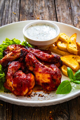 Buffalo wings with ranch dressing and French fries on wooden table
