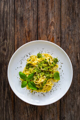 Tagliatelle with basil pesto sauce on wooden table
