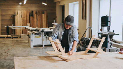 Carpenter works with wood in carpentry workshop. Man doing woodwork professionally