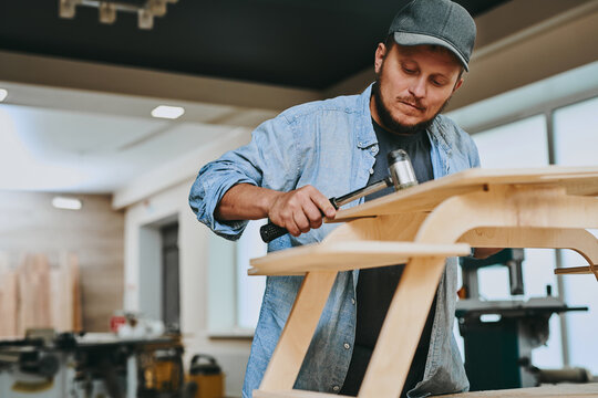 Carpenter works with wood in carpentry workshop. Man doing woodwork professionally