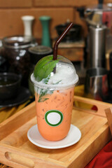 Cannabis milk tea, a cooling drink with cannabis as an ingredient, is placed on a classic wooden table in a glass decorated with beautiful cannabis leaves. Recreational cannabis concept.