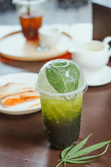 Cannabis Lime Soda Cooling drinks with cannabis as an ingredient are placed on a classic wooden table in glasses decorated with beautiful cannabis leaves. Recreational cannabis concept.