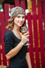 Beautiful young woman drinking white wine on the terrace of a restaurant. Relaxing after work with a glass of wine. Single woman having fun.