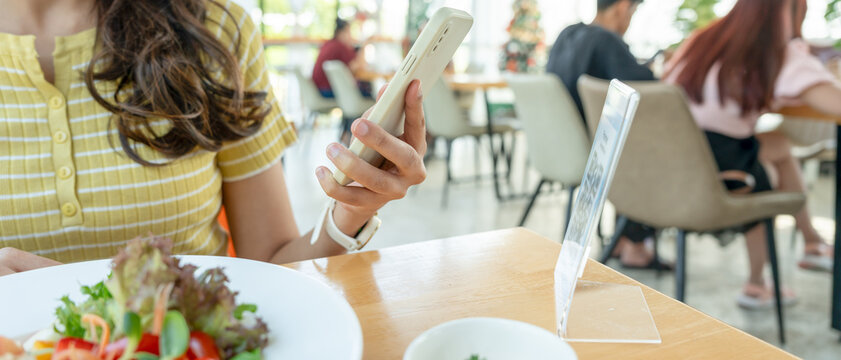 Woman use smartphone to scan QR code to pay in cafe restaurant with a digital payment without cash. Choose menu and order accumulate discount. E wallet, technology, pay online, credit card, bank app.