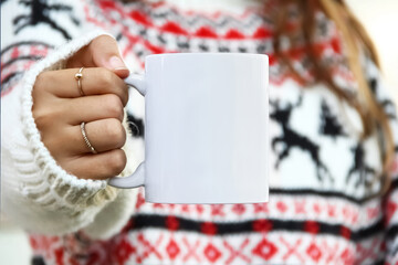 Girl is holding white mug in hands with christmas sweater. Blank 11 oz white xmas copy space...