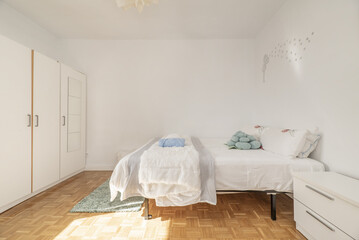 Bedroom with a large double bed with a white wardrobe with mirrors and slatted parquet floors laid in a checkerboard pattern