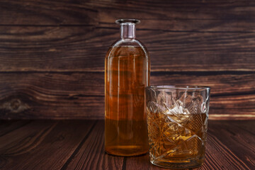 a bottle of liquor next to a cut glass with ice