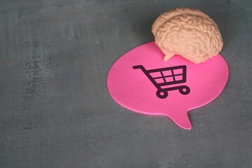 A human brain and speech bubble with shopping carts icon. Consumer behavior, impulse buying and...