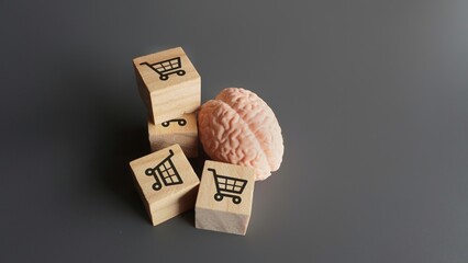 A human brain and wooden blocks with shopping carts icon. Consumer behavior, impulse buying and shopping addiction concept. - obrazy, fototapety, plakaty