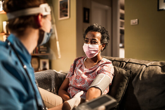 Senior African American woman getting her blood pressure checked by a caregiver at home