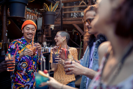 Young and diverse group of friends having drinks together in a bar in the city