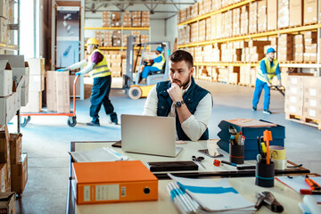 Young male warehouse supervisor working on a laptop