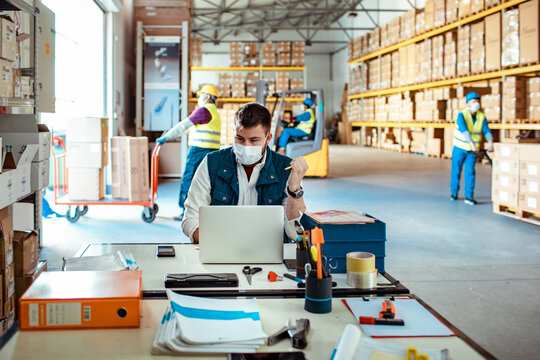 Young male warehouse supervisor working on a laptop
