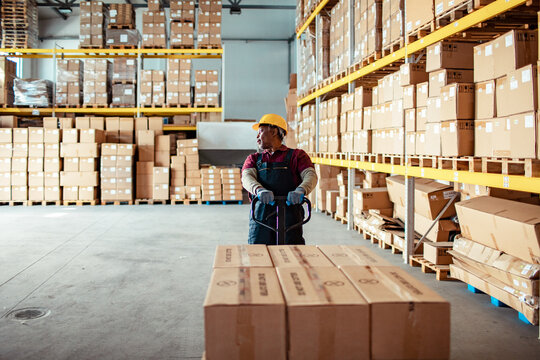 Senior African American worker pushing a rolling cart with boxes in a warehouse