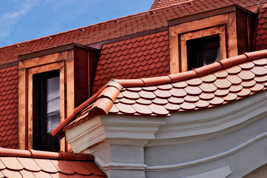 beavertail clay tile sloped residential roofs. bright shiny new copper plated roof dormers. new construction. closeup view. reflective glass window. mansard roof. modern house architecture.