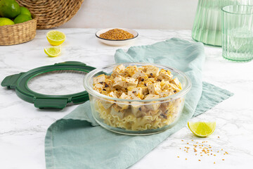 Tupperware filled with pasta with tofu and sesame. Cooked at home.