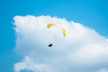 An adrenaline-pumping extreme sport, paragliding against the clear blue sky. Paraglider flying with...