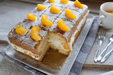 Orange cake with cream and tangerines on a white background. 