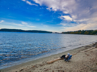 Men sitting on a banch be the sea reading book. 