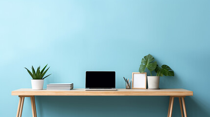 Minimal home office table with a blue background, the laptop is on the wooden table with the green flower in vase