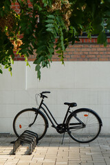Fototapeta na wymiar Black retro bicycle parked on bike rack in front of brick wall in Bucharest