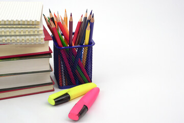 Fototapeta premium Crayon or colored pencils in box with side stack of books and school supplies on with background. Learning, study and office equipment concept.