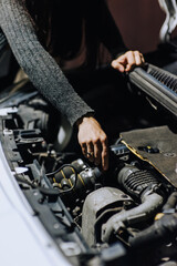 A woman mechanic repairs a car with a breakdown in the engine at night. Photography, close-up portrait.