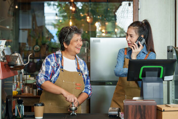 Retired single mother businesswoman grinds coffee beans  smiles Asian daughter in front of coffee...