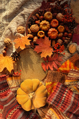 autumn background. Decorative pumpkin shape candles, acorns, nuts, fall leaves, knitted socks on plaid backdrop. Fall season. symbol of harvest, Mabon, thanksgiving, Halloween. top view. copy space