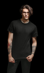 Hipster handsome male model with glasses wearing black blank t-shirt and black jeans with space for your logo over black background