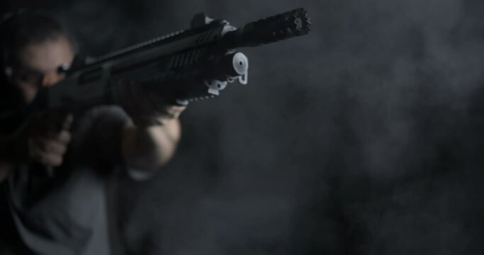 Close-up of man aiming and firing a shotgun in high-speed with smoke flying everywhere. powerful impact shot in slow-motion