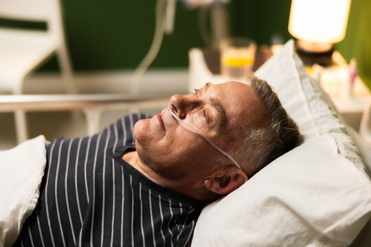 Close-up of an elderly patient peacefully asleep, with an oxygen tube in his nose and an open mouth in hospital