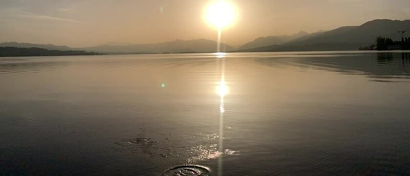lobbing of stone on water during sunrise on zurich lake (zurich see) Switzerland, horizontal orientation