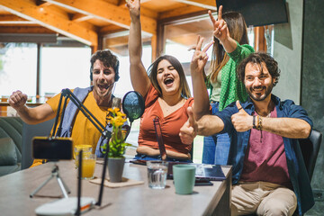 Four Friends Celebrate Victory During a Live Stream - Enthusiastic content creators cheer and gesture, engaging with their audience while recording a video blog using a smartphone and microphone.