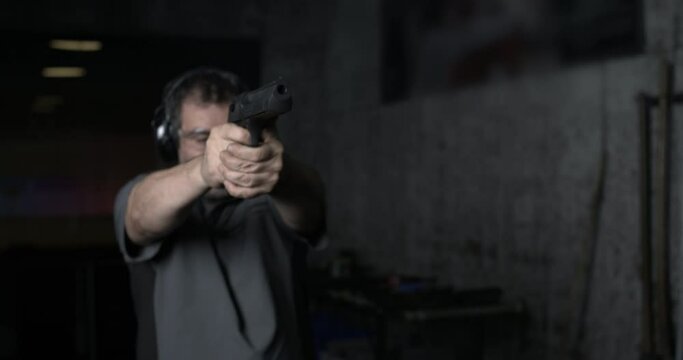 Man aiming and firing with Desert Eagle gun in high-speed slow-motion at 800 fps at shooting range training. Person practicing with weapon