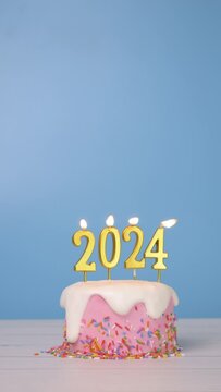 Happy New Year 2024, seamless looping of cute cake with golden candle number 2024 for new year celebrate party was lit. flame at candlewick sway and flicker with blue background, vertical