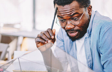 Thoughtful black man staring at glass terrarium in office